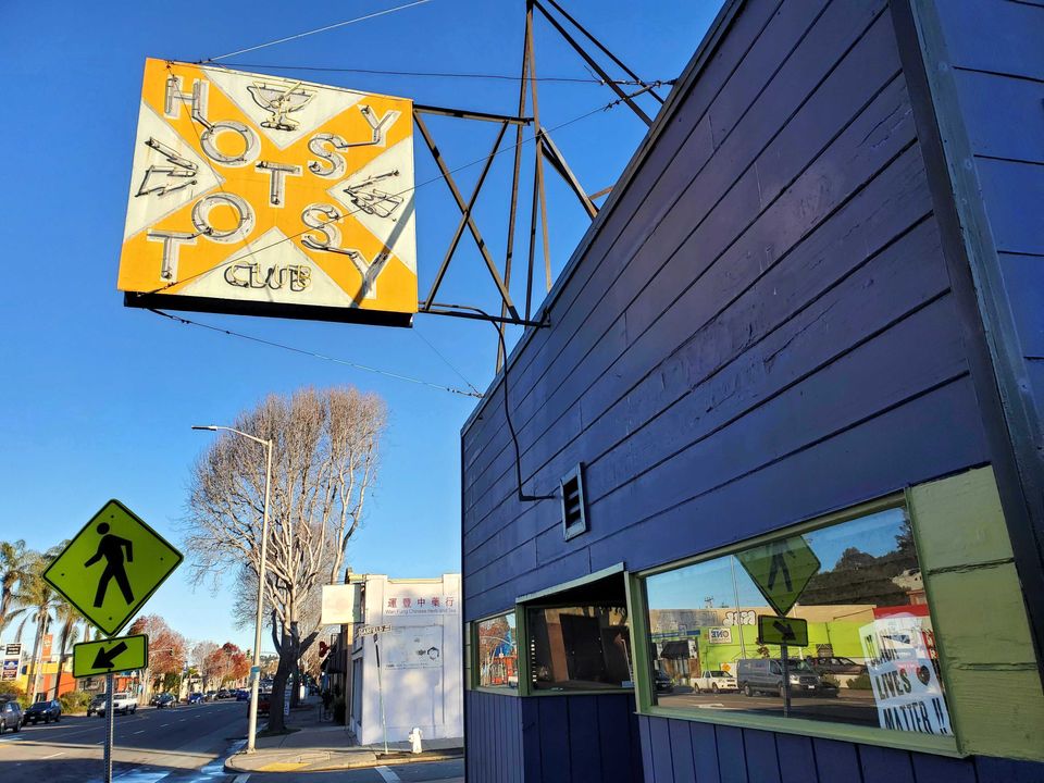 Exterior view of the front of the Hotsy Totsy Club with overhead sign inspired by a Confederate symbol.